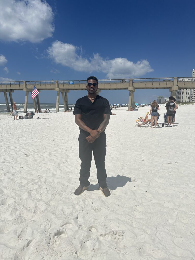 a man in black dress standing on the beach