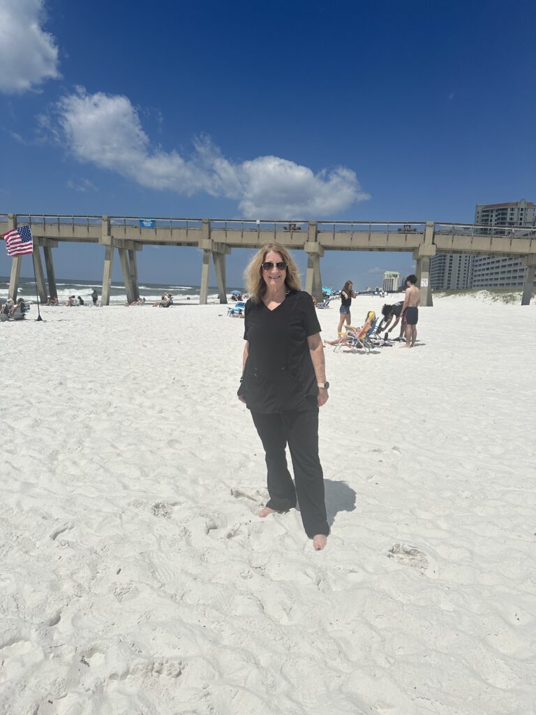 A woman in black dress wearing sunglass standing in the beach